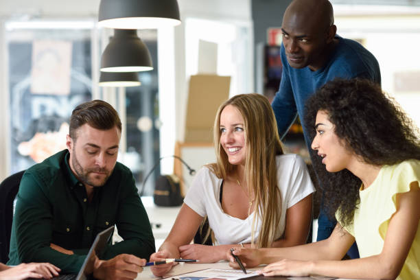 Four young people working together. Beautiful men and women in a business meeting wearing casual clothes. Multi-ethnic group.