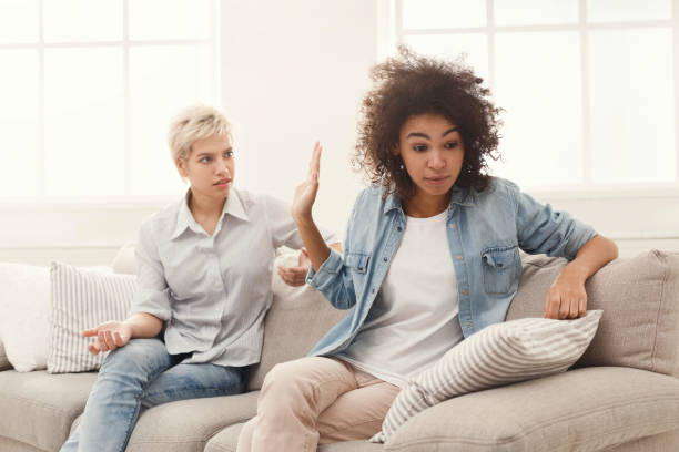 Two female friends sitting on sofa and arguing with each other. Friendship, quarrel, female disagreement, copy space